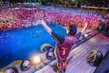 A person on stage gestures to a huge crowd of people in a pool in Wuhan, during a music festival.