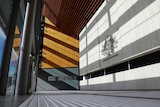 Geometric lines and shadows in entrance of building made of concrete and wood panelling.