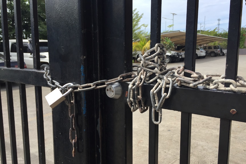 Black gates locked together with chain-link and a padlock