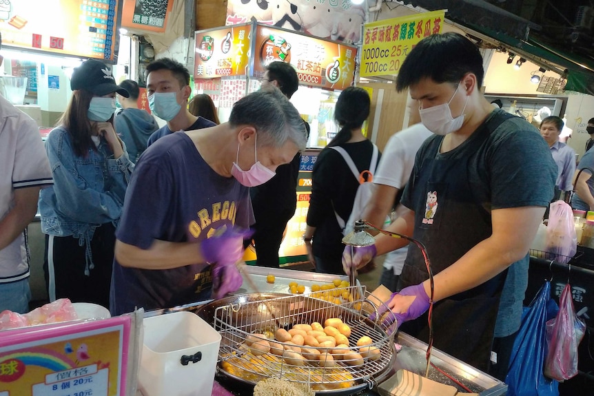 台北夜市上，小贩们戴着口罩，以防止新冠病毒的传播。