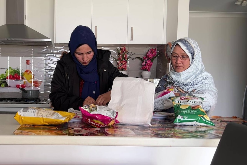 three Afghan women prepare food in a kitchen