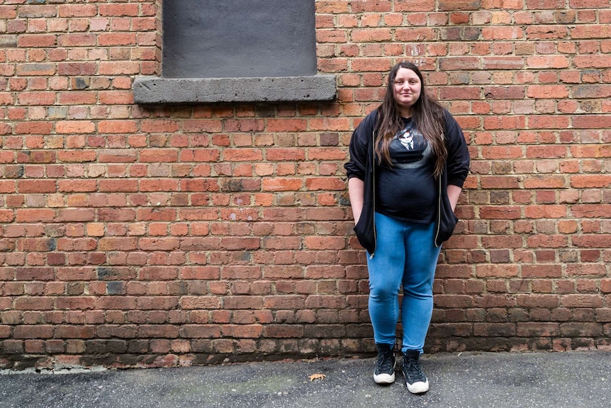 Natasha Anderson, an advocate for care leavers standing with her back to a brick wall.