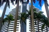 A tall white and black building that says 'The Star' at the top, with tall palm trees in the foreground against blue sky