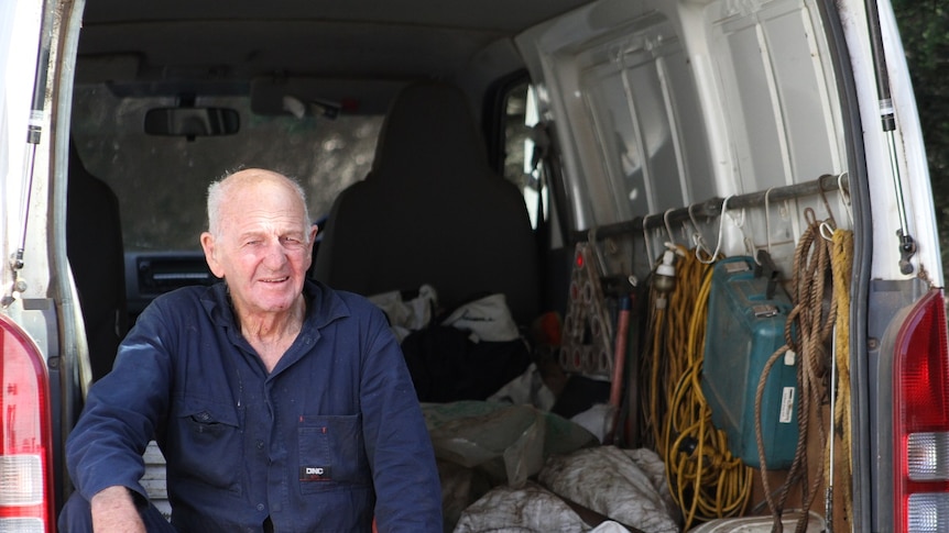 Elderly man sits in back of truck