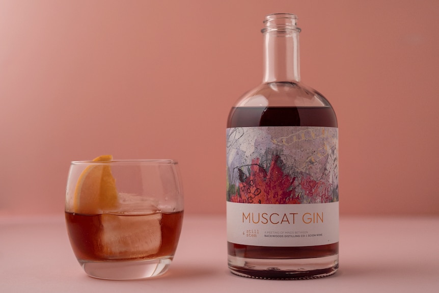 a glass and bottle of magenta colour gin 