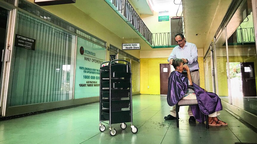 Longreach hairdresser Gaby Janho cuts the hair of a female customer in the arcade area while to power is off.