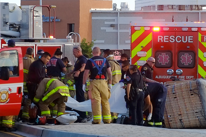 Lucrătorii de salvare ajută răniții pe o stradă cu vehicule de urgență parcate în jurul lor.