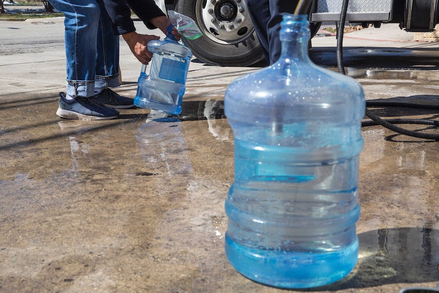 Residents fill up jugs at a water station in Texas