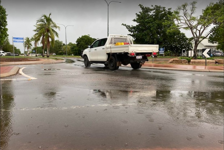 A ute drives around a roundabout in rainy weather in Broome