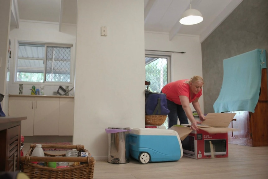 A woman packs boxes in her home.