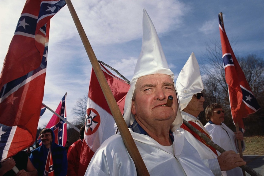 A male member of the Ku Klux Klan smokes a cigar during a rally.