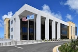 An imposing modern courthouse in a picturesque setting, with the ocean in the background.