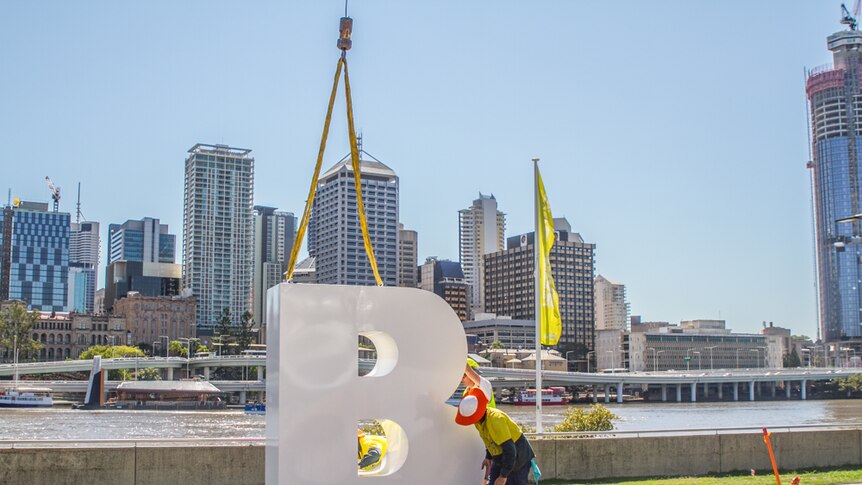The letter B is put in place guided by engineers on the Brisbane River.