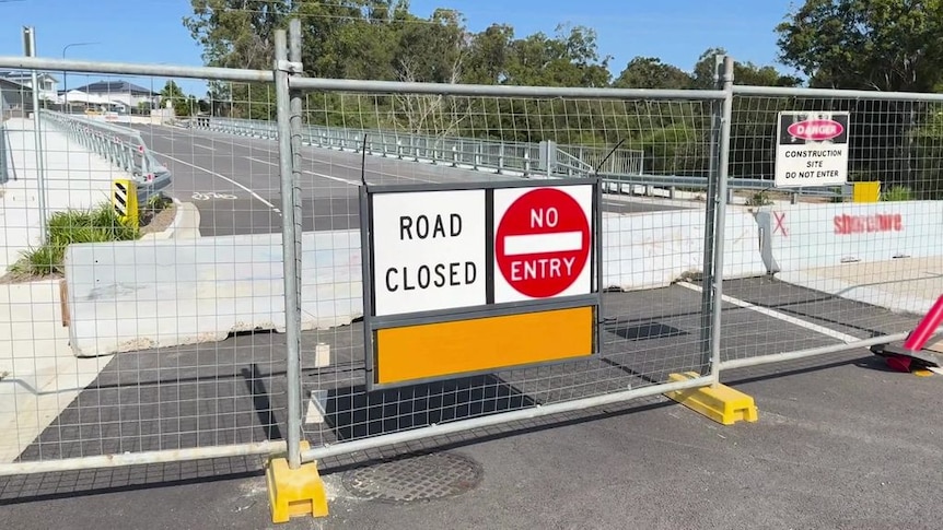 A bridge blocked by fencing and concrete, with a sign that reads "road closed".