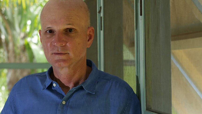 A photo of architect David Bridgman leaning against the louvres in his home.