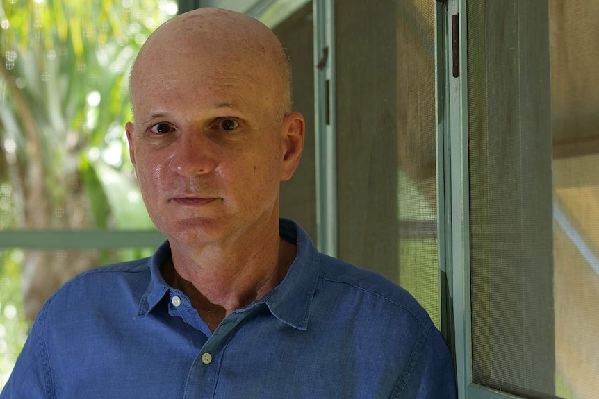 A photo of architect David Bridgman leaning against the louvres in his home.