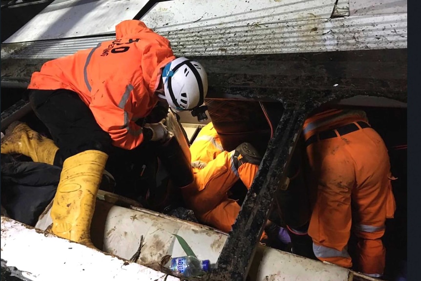 Rescuers search for survivors and victims inside the wreckage of a bus