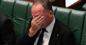Deputy Prime Minister Barnaby Joyce with his heads in his hands during Question Time, sitting on the green leather benches