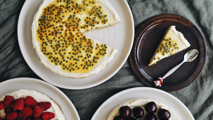 Three no-bake cheesecakes, one topped with cherries, one with raspberries, the other passionfruit, an easy summer dessert.