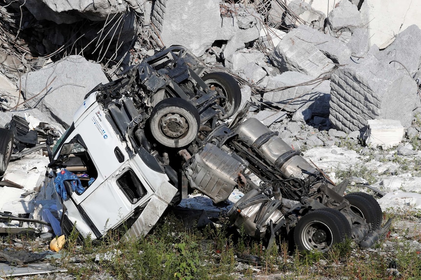 A crushed truck is surrounded in rubble and concrete.