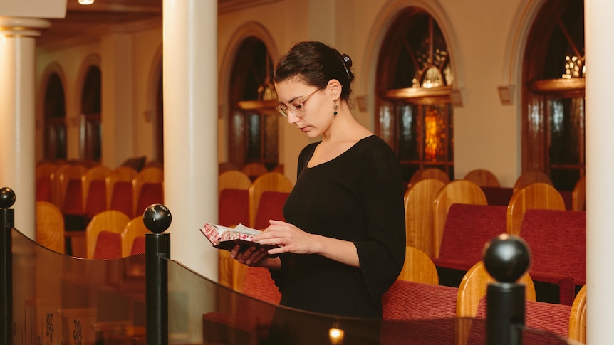 Nicky Gluch reading Torah standing in Sephardic Jewish synagogue.