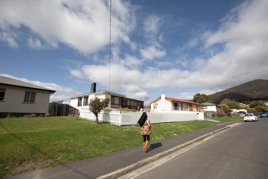 A woman with black hair approaches a suburban house