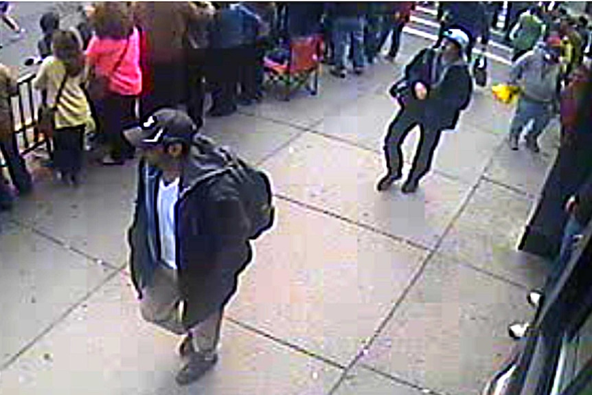 Suspects One and Two walk through the crowd.