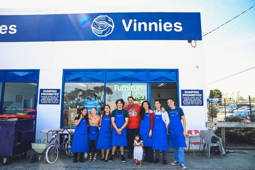 A group of volunteers stand smiling out the front of a Vinnies Shop