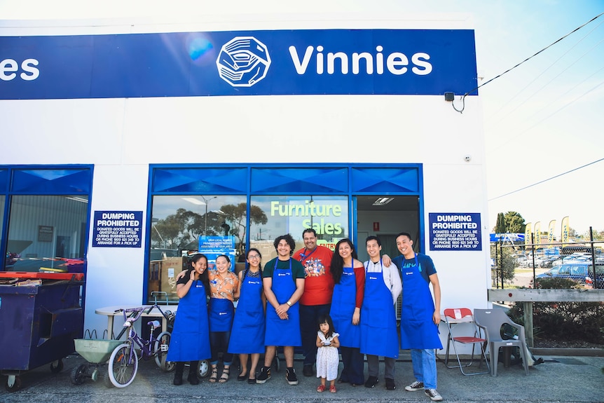 Un grupo de voluntarios sonríe frente a una tienda Vinnies