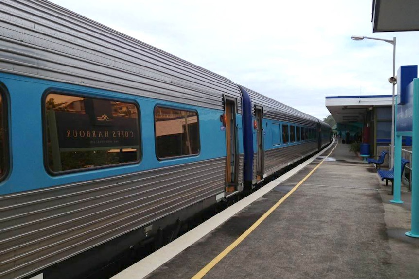 Silver and blue train carriages stopped at a station.