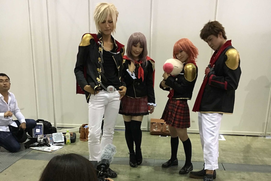 Group in costume pose for a photo at the games exhibition