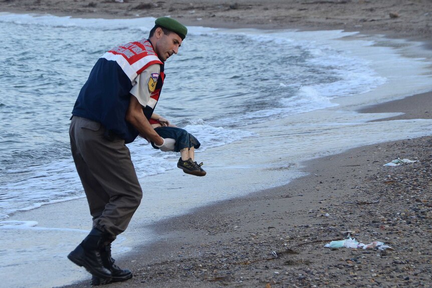 Alan Kurdi's body is carried from the beach by a Turkish police officer.