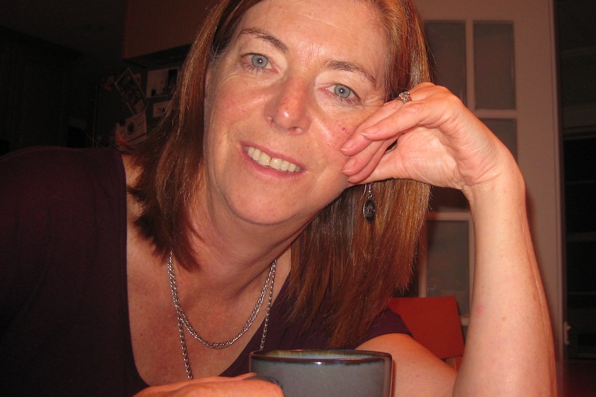 A photo of a woman smiling at the camera with a cup of tea