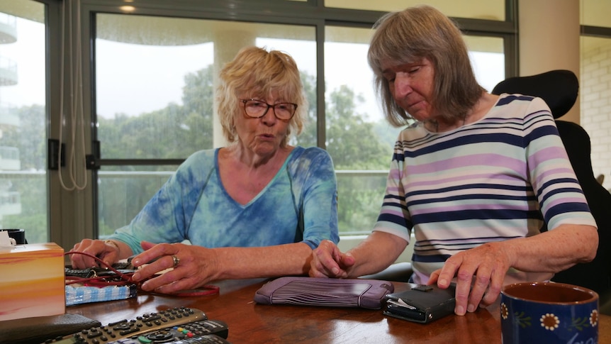 Two women in their 70s interacting at a table