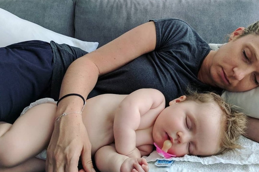 Rachael sleeps on the couch with her baby daughter, Mackenzie.