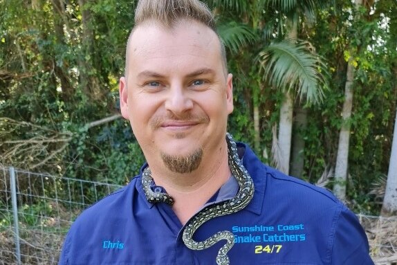Man standing with small snake around his neck
