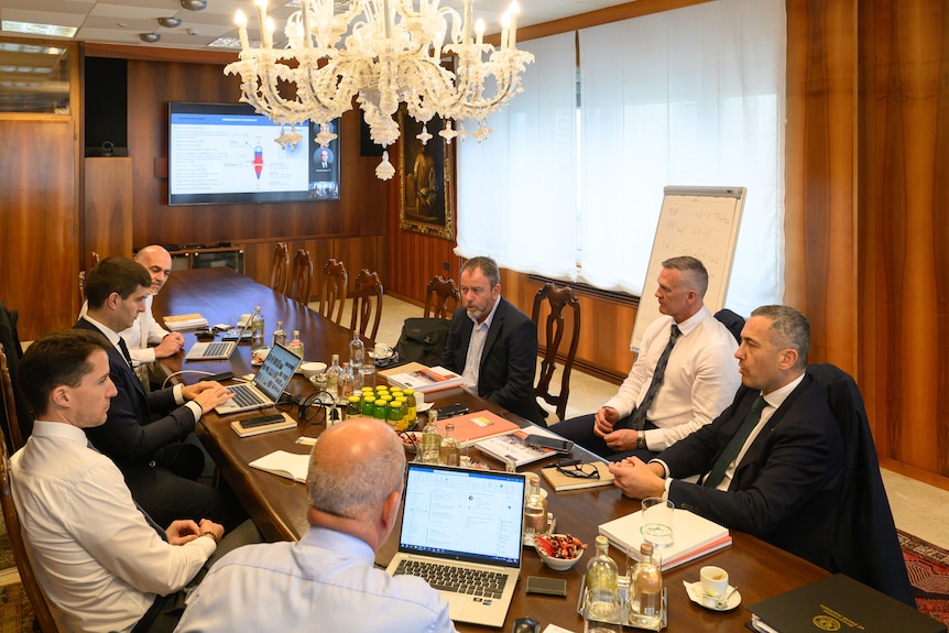 A group of men in a lavish looking boardroom.