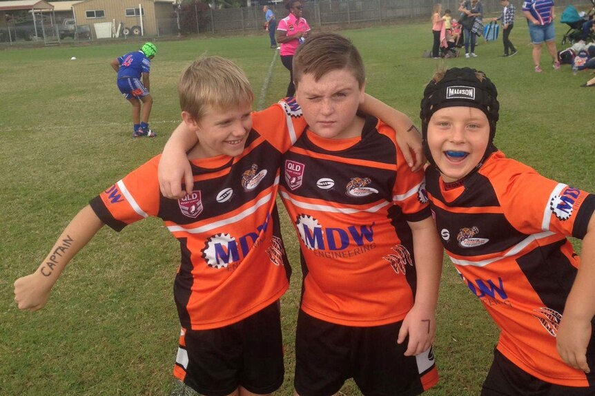 Three young boys in orange football gear. 