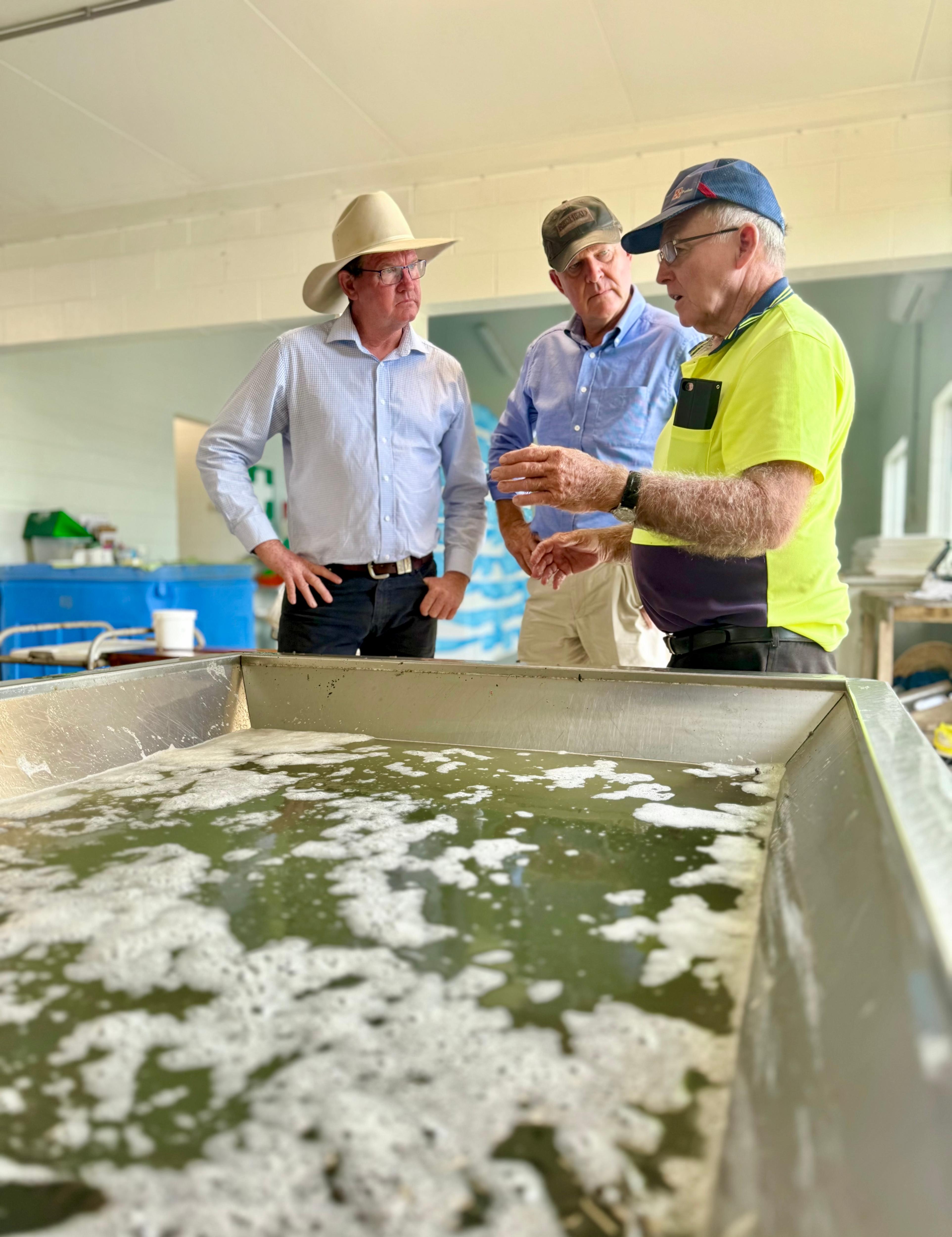 Tres hombres hablan detrás de una gran tina de agua.
