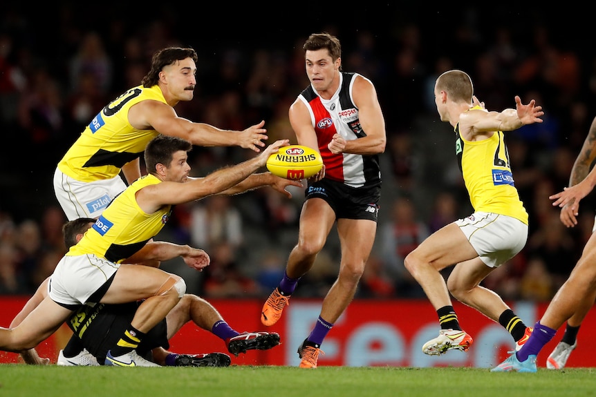 Jack Steele tries to handball but is smothered by three Tigers players.