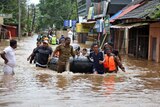 Rescuers evacuate people from a flooded area to a safer place in Aluva.
