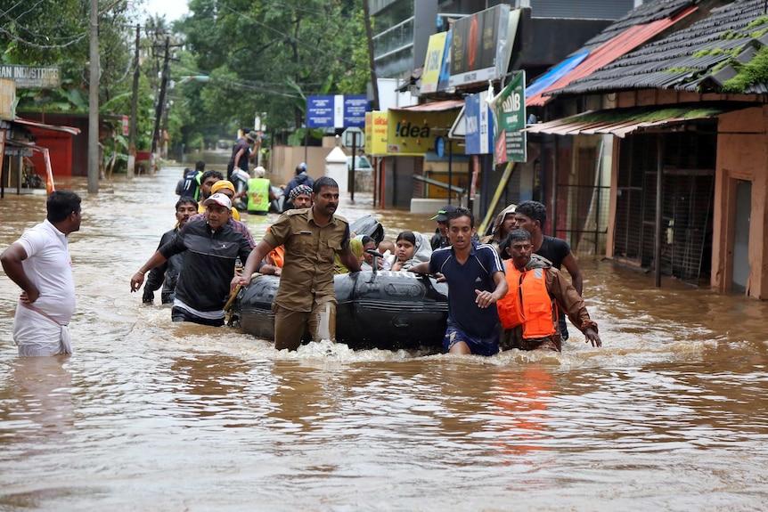 Rescuers evacuate people from a flooded area to a safer place in Aluva.