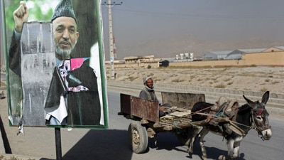 File photo: Man rides donkey past Karzai poll poster in Kabul (Reuters: Ahmad Masood)