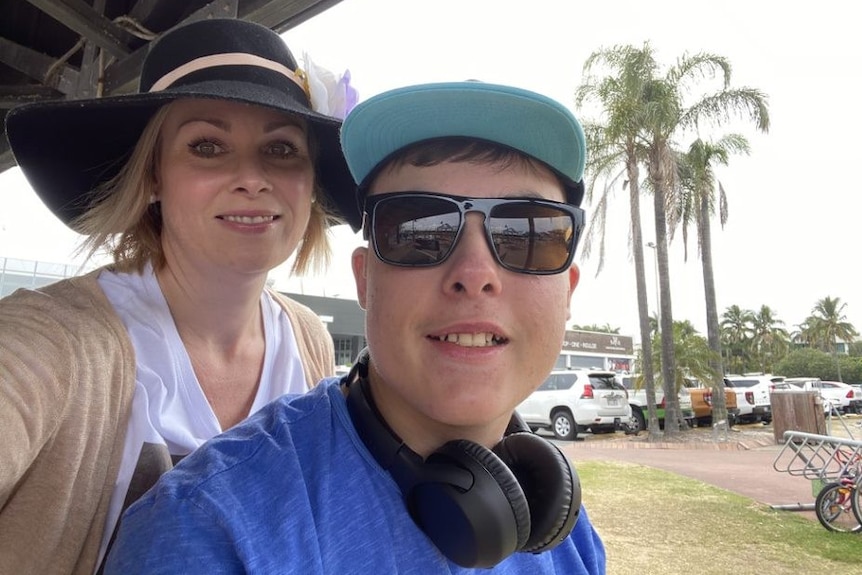 A woman smiles with a young boy wearing sunglasses.