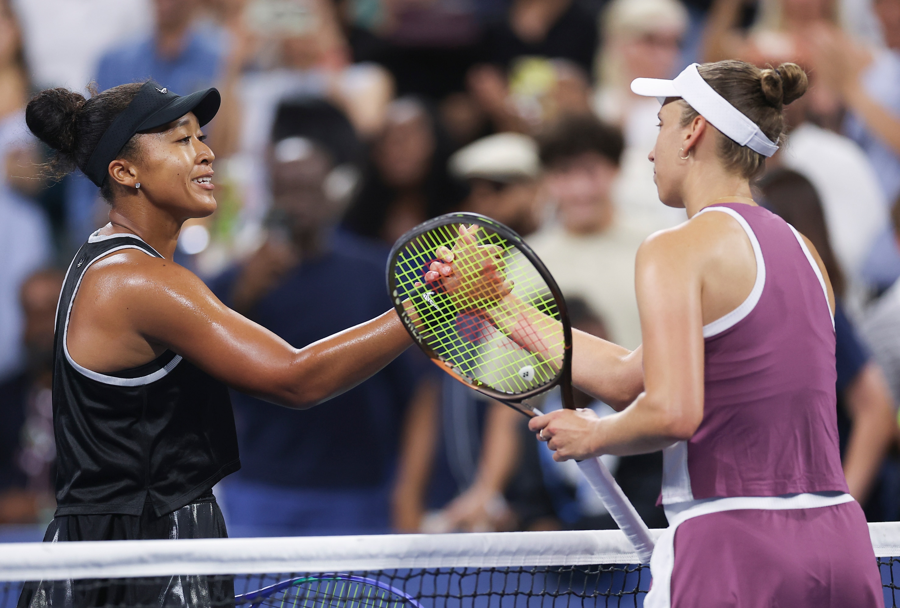 Naomi Osaka and Elise Mertens greet each other at the net.