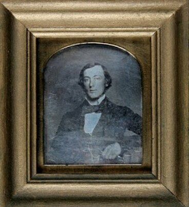 An old photo in a large gold frame of Alfred Bock