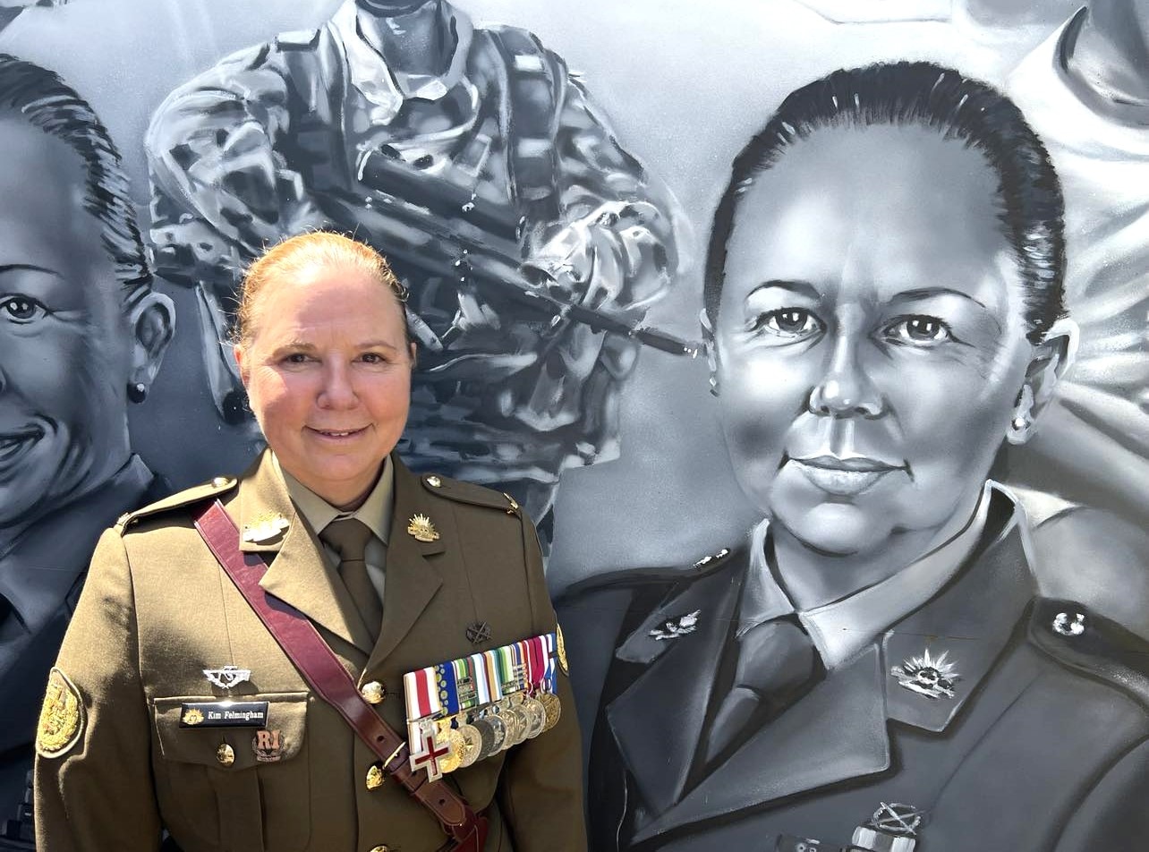 A women stands beside a painted picture of herself on a mural 