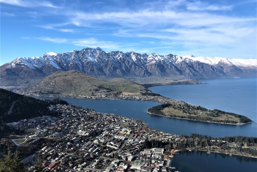 Aerial shot of a lakeside city with a snowy mountain range in the background