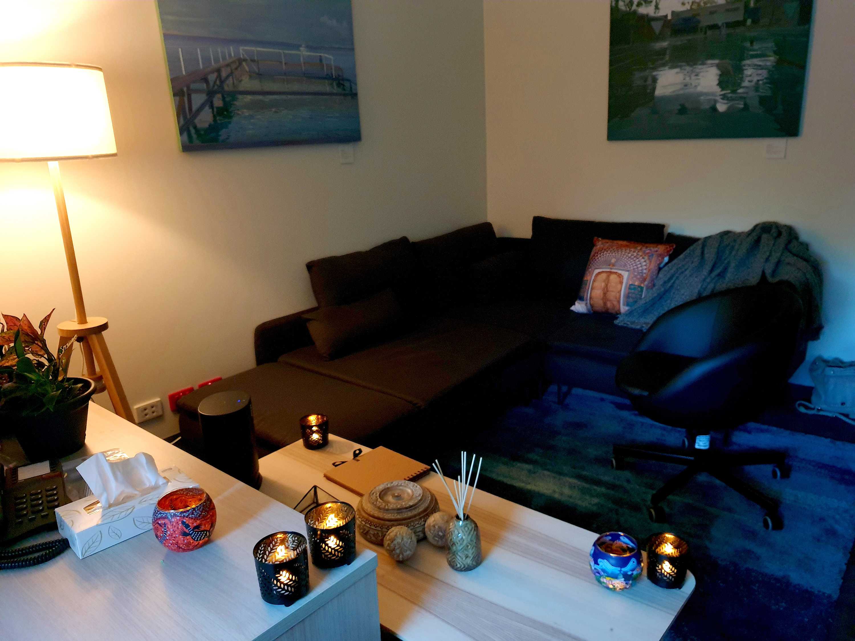 A small low lit room in St Vincent's, with a couch, blanket, candles, paintings and phone.