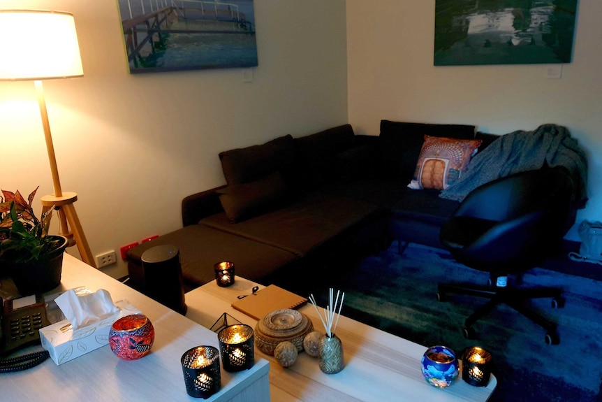 A small low lit room in St Vincent's, with a couch, blanket, candles, paintings and phone.